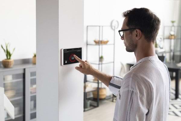 Homme qui utilise un thermostat d'ambiance